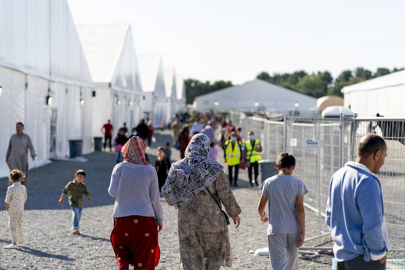 Afghan refugees walk through an Afghan refugee camp at Joint Base McGuire Dix Lakehurst, N.J., on Sept. 27, 2021.