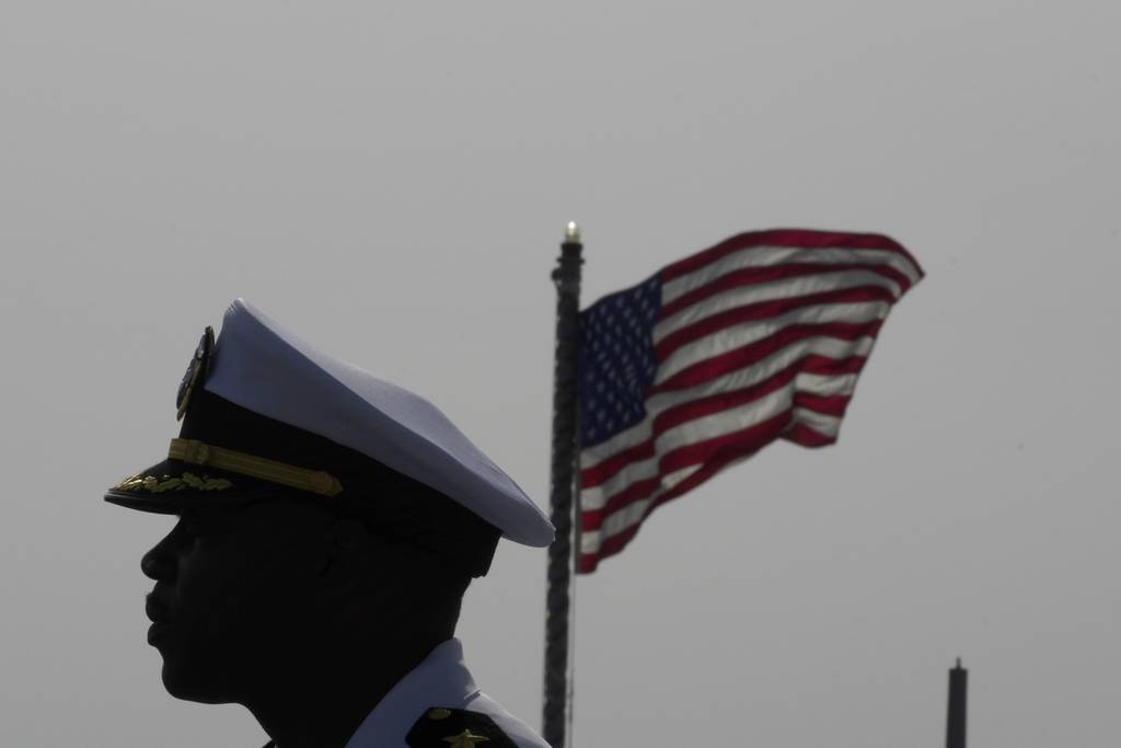 Cmdr. Executive Officer Tyrchra Bowman stand in front of U.S flag on the missile destroyer USS Arleigh Burke, docked in the port in southern city of Limassol, Cyprus, Wednesday, May 17, 2023.